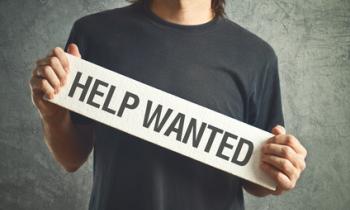 Guy holding a "help wanted" sign