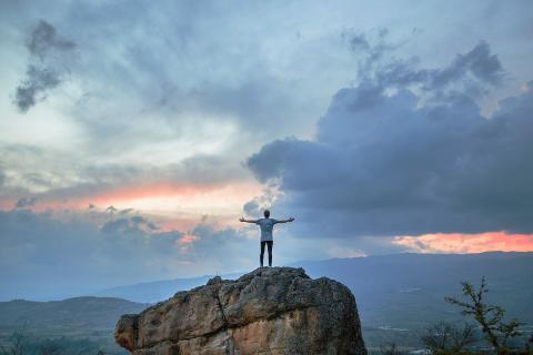 Man on mountain praising God